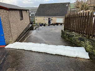 FloodSax alternative sandbags protecting a house from water running down a driveway